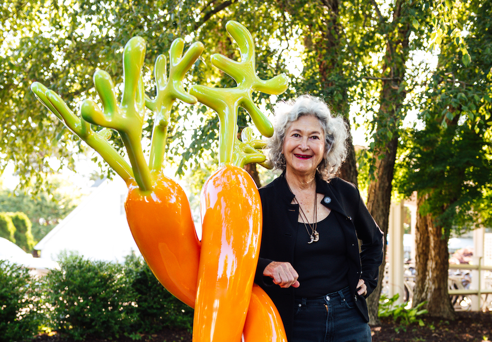 Artist Jan Kirsh standing next to her 6-foot sculpture, Patricia's Carrots